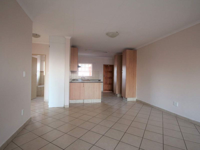 An open-plan living and kitchen area featuring tiled flooring, built-in cabinetry, and a functional kitchen layout with a hob and extractor fan.