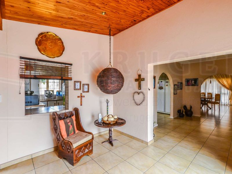 Open plan living area featuring a timber ceiling, tiled flooring, and a convenient serving hatch connecting to the kitchen space.