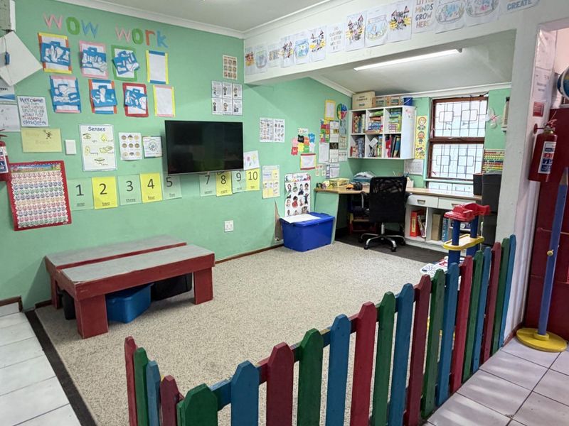 A multi-purpose room currently utilized as a classroom, featuring built-in desk space, shelving, and security bars on the window.