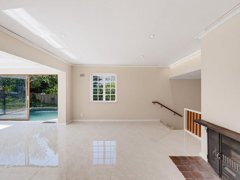 Spacious, light-filled living area featuring polished tile floors, a built-in fireplace, and seamless access to the outdoor pool area through large sliding glass doors.