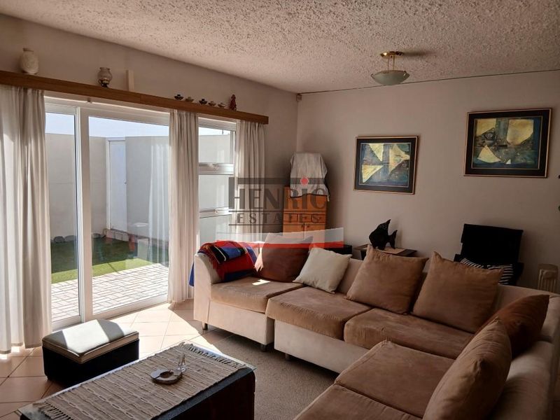 A living room featuring tiled flooring and a large sliding glass door providing access to an outdoor patio area.