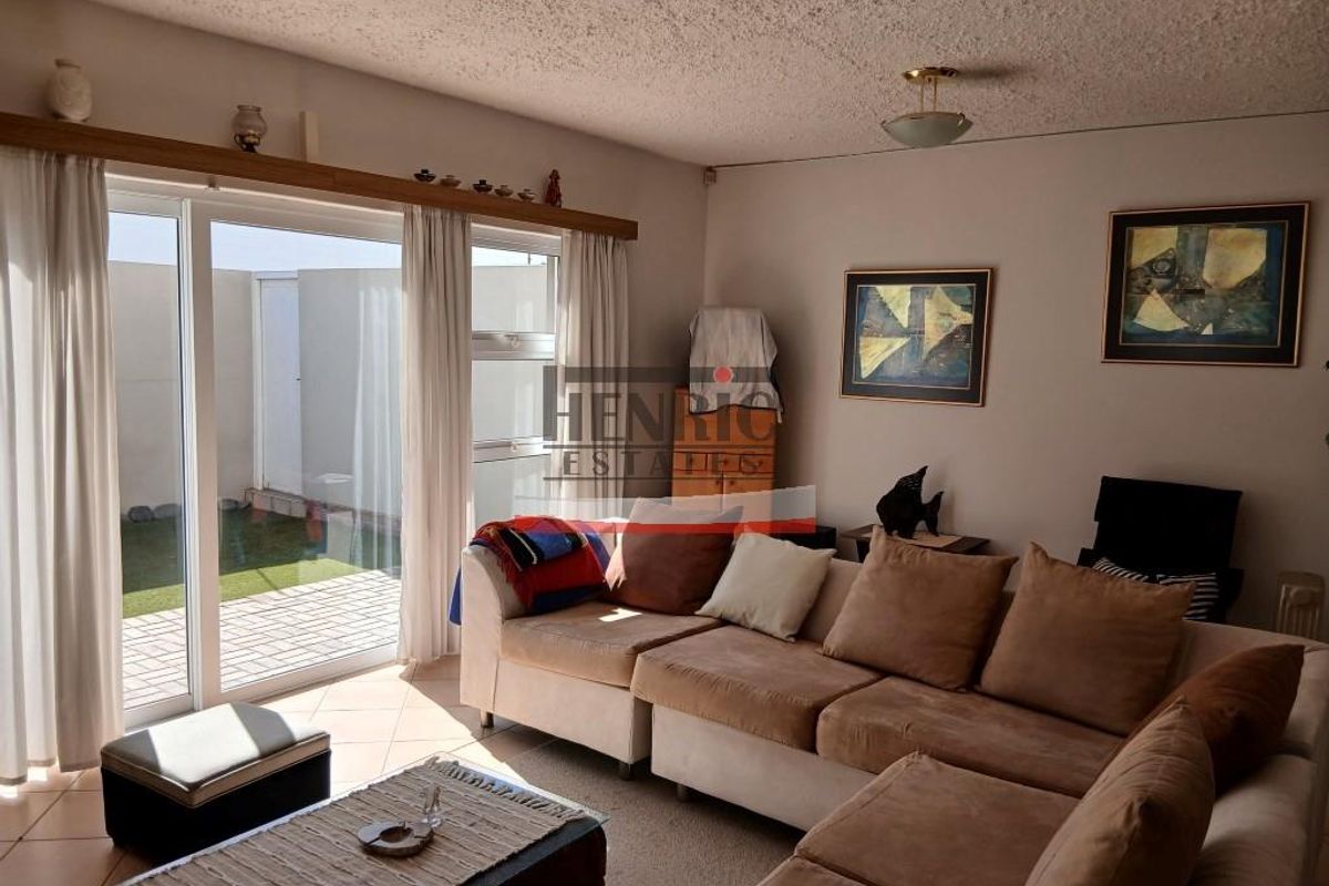 A living room featuring tiled flooring and a large sliding glass door providing access to an outdoor patio area.
