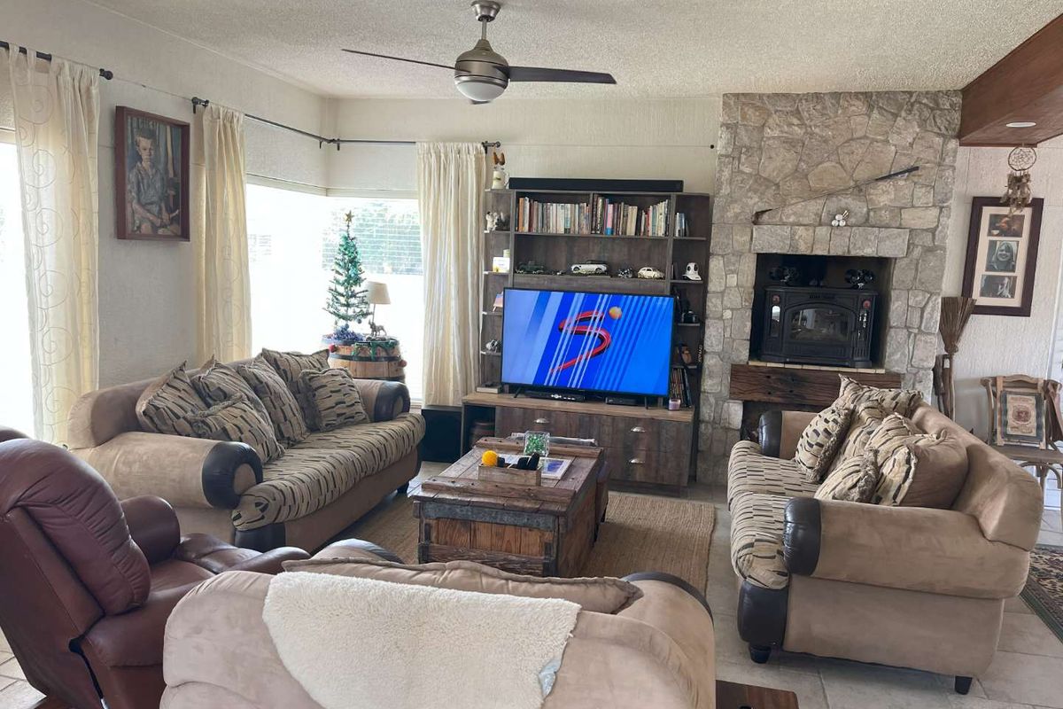 Spacious living room featuring a prominent stone-clad fireplace with a built-in wood-burning stove and tiled flooring.