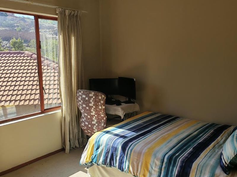 A functional bedroom featuring carpeted flooring and a large window with natural light, providing a comfortable space for rest or study.