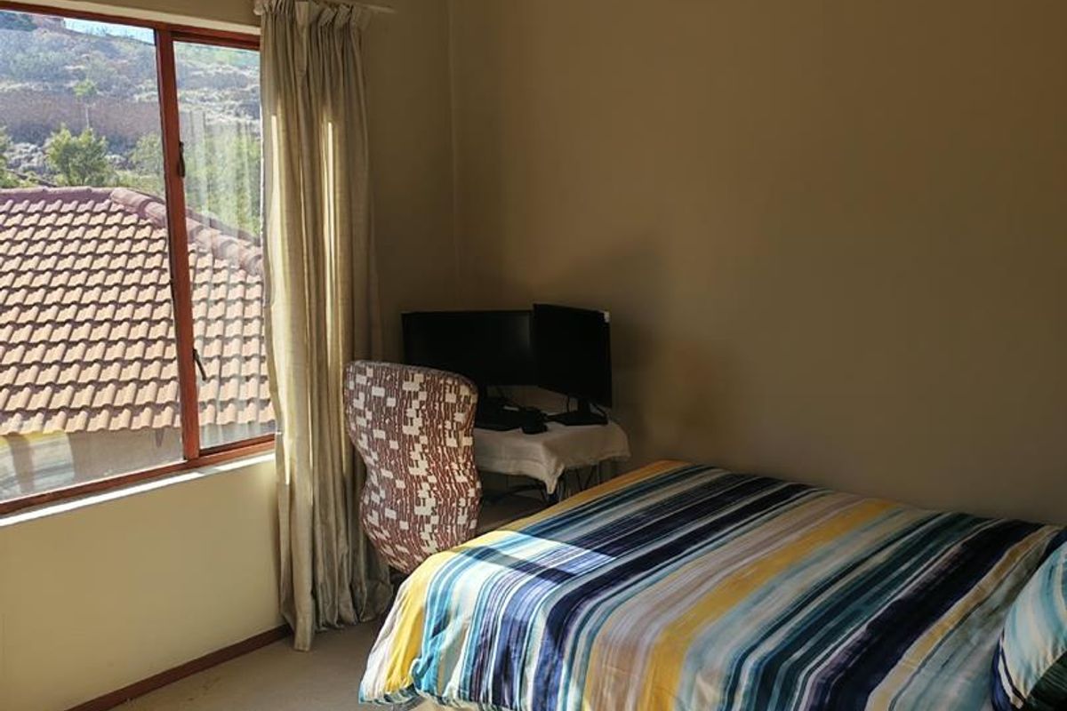 A functional bedroom featuring carpeted flooring and a large window with natural light, providing a comfortable space for rest or study.
