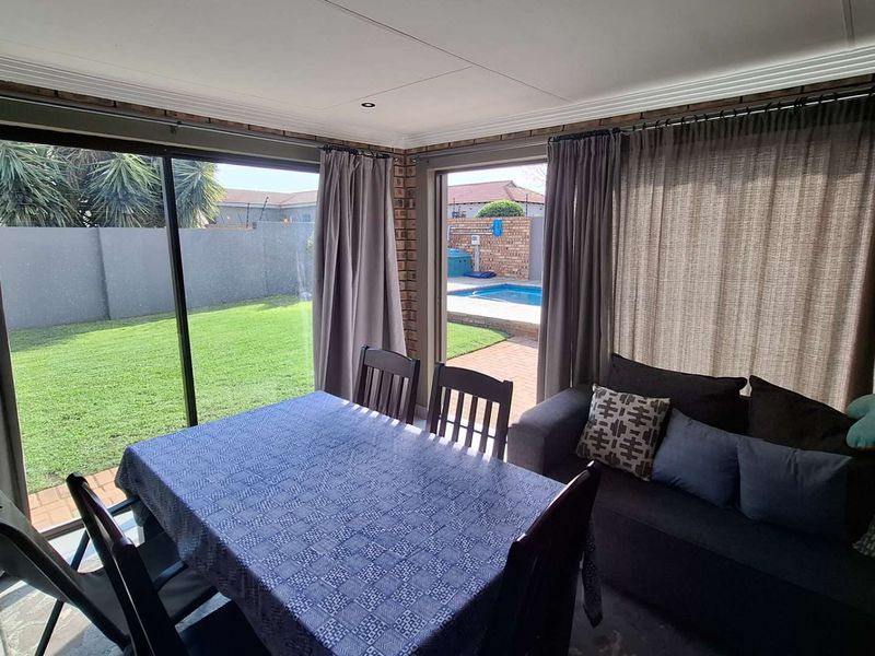 Enclosed patio area featuring large sliding glass doors, exposed brickwork, and direct access to the garden and swimming pool.