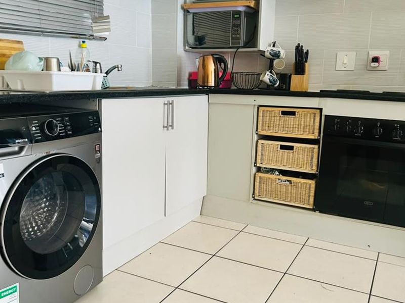 A functional kitchen featuring white cabinetry, integrated oven, extractor fan, built-in microwave, tiled backsplash, and tiled flooring.