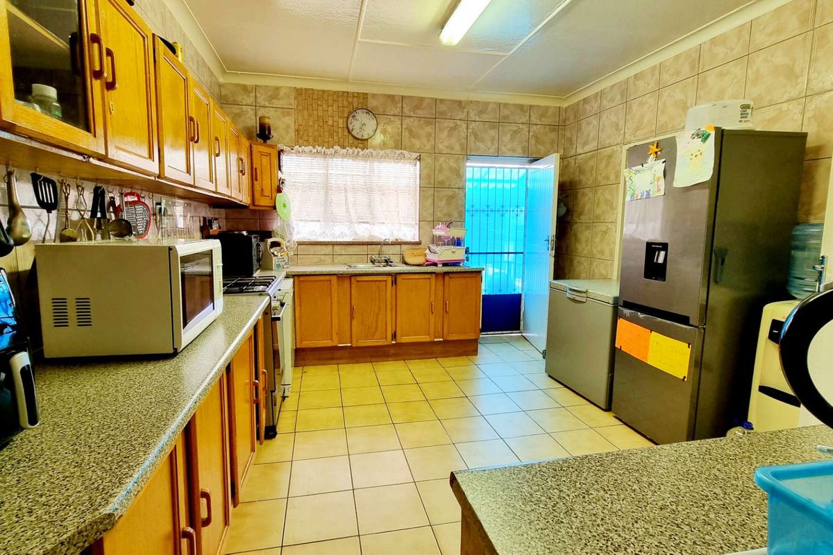 A functional kitchen featuring wooden cabinetry, tiled walls, and tiled flooring with direct access to the exterior.