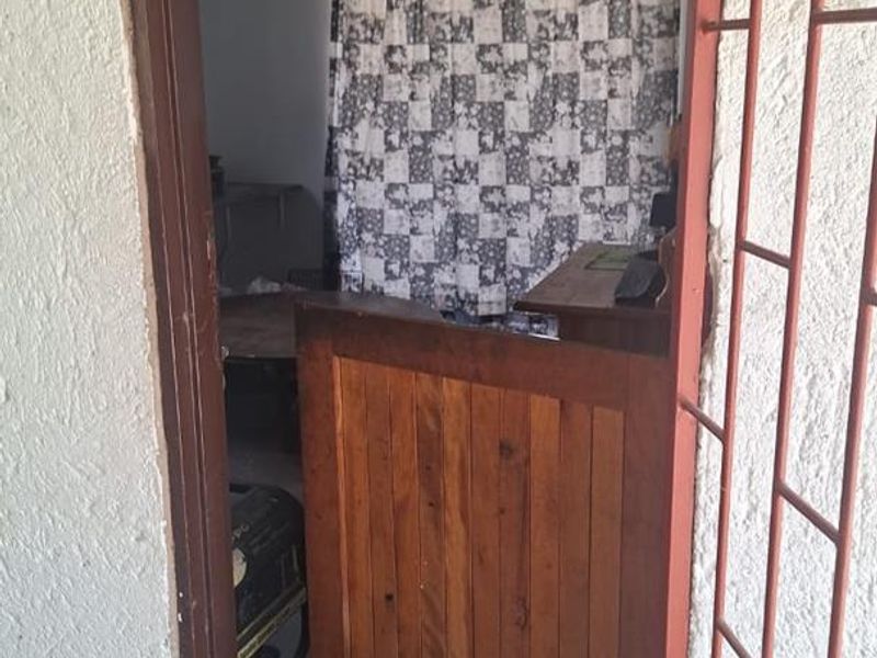 A utility space featuring a wooden stable door and security gate, showing signs of wear and requiring maintenance to the wall finishes and threshold.