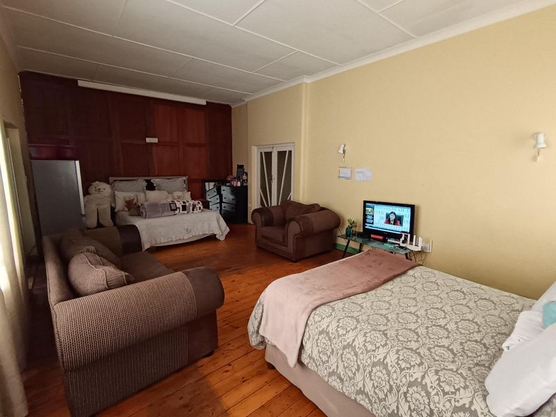 Spacious bedroom featuring original timber flooring and decorative timber wall paneling, offering a classic aesthetic with potential for modernization.