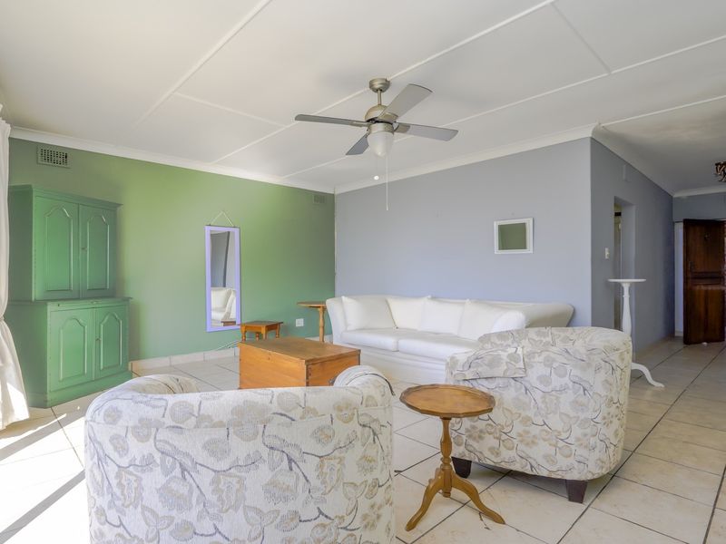 A spacious living room featuring tiled flooring, a ceiling fan, and large sliding glass doors that provide ample natural light.