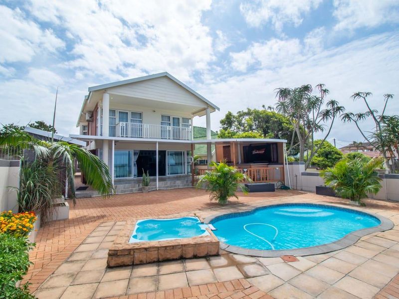 Spacious rear garden featuring a swimming pool, built-in spa, paved patio area, and a two-story townhouse with a balcony.