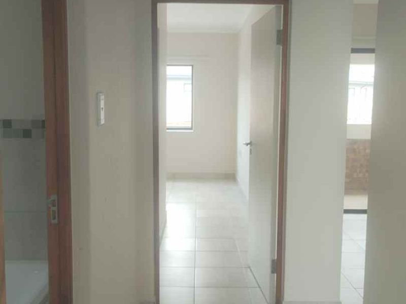 A bright, empty hallway with tiled flooring connecting multiple rooms within the apartment.