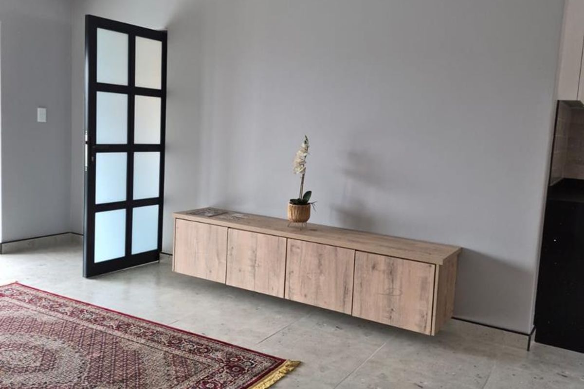 A modern living area featuring neutral grey walls, large format tiled flooring, and a contemporary floating wooden media console.