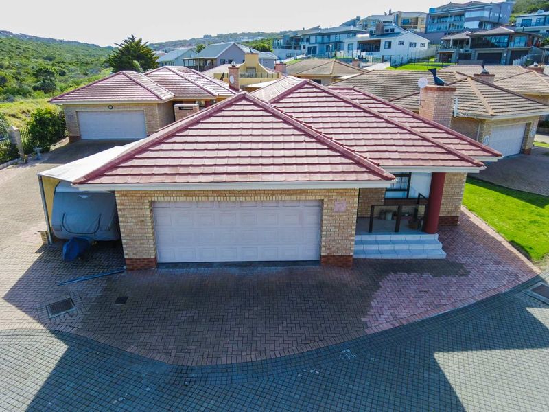 Aerial view of a brick townhouse featuring a tiled roof, double garage, and paved driveway within a residential estate.