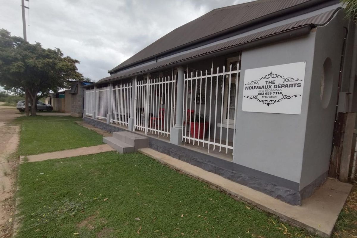 Front elevation of a property featuring a covered veranda, security fencing, and a corrugated iron roof.