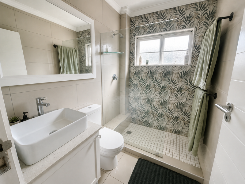 Modern bathroom featuring a vessel sink vanity, a walk-in shower with patterned tile accents, and neutral wall tiling.