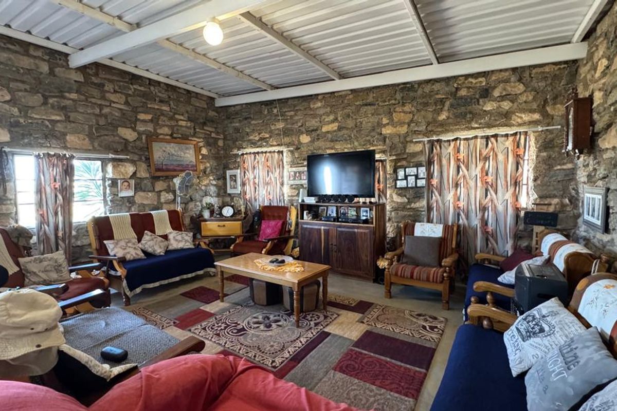 Rustic living room featuring authentic exposed stone walls and a high exposed beam ceiling with corrugated metal roofing.