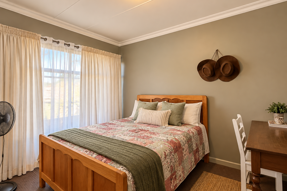A well-maintained bedroom featuring neutral wall tones, carpeted flooring, and a large window with curtain treatments, providing a comfortable and functional living space.