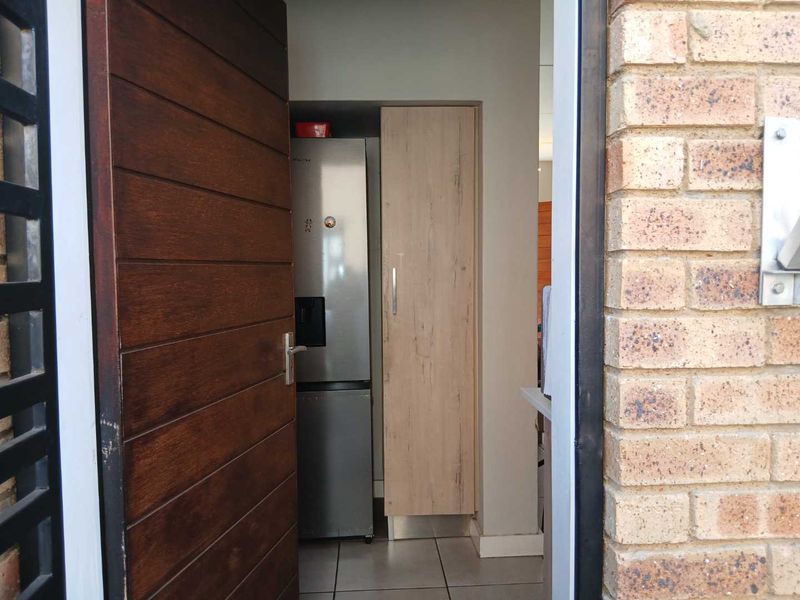 View through the timber front door into the interior, featuring tiled flooring and built-in cabinetry.