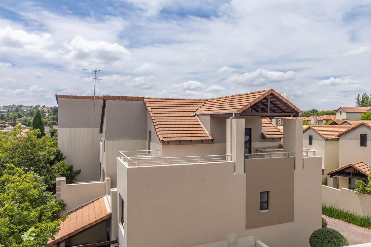 An elevated aerial view of the apartment building exterior, showcasing the tiled roof structure, balcony area, and modern facade finishes.