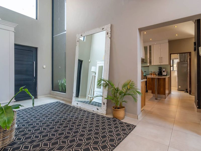 Spacious entrance hall with double-height ceilings, large windows, and tiled flooring, providing a bright and welcoming transition into the home's living areas.