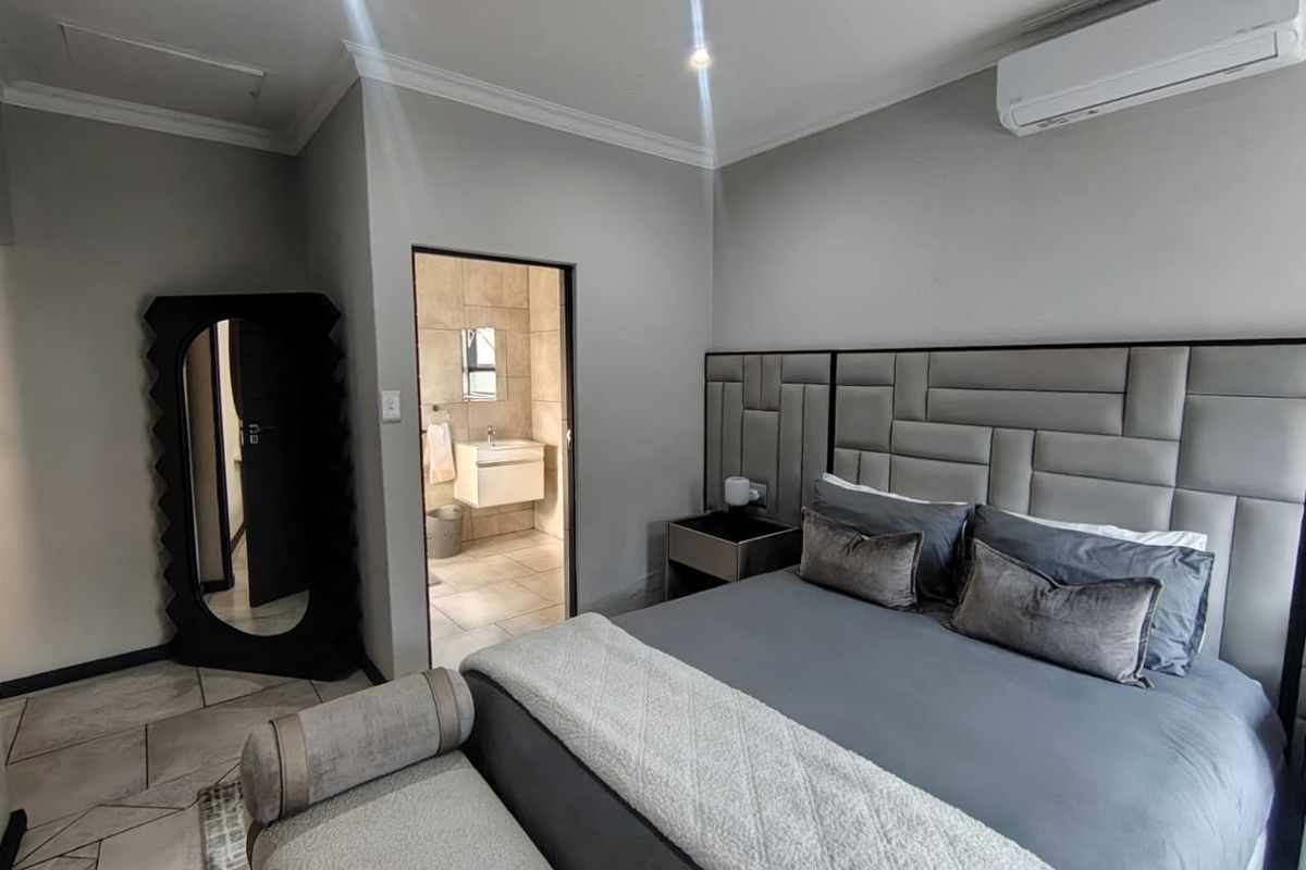 Modern bedroom featuring tiled flooring, recessed lighting, a split-system air conditioner, and an adjoining en-suite bathroom with a wall-mounted vanity.