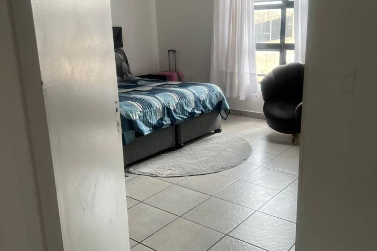 A bedroom featuring tiled flooring and a window, viewed from the doorway.