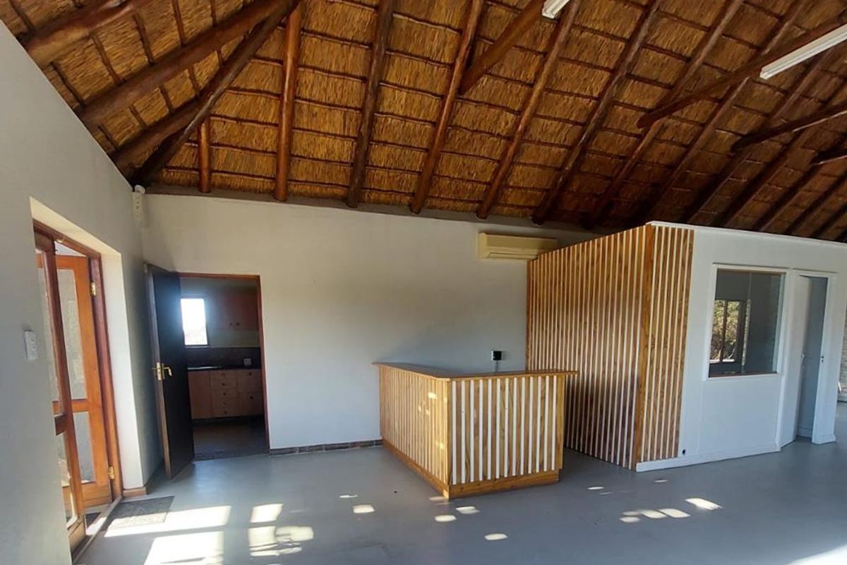 Spacious office area featuring a high vaulted thatched ceiling, exposed timber beams, a built-in reception counter, and integrated air conditioning unit.