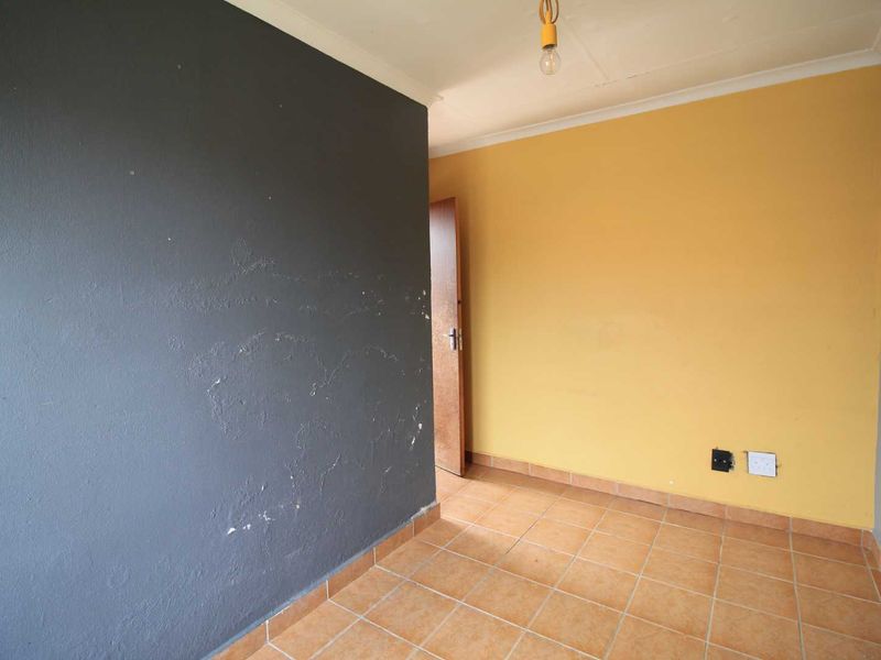 An empty bedroom featuring tiled flooring and contrasting painted walls, requiring minor cosmetic updates to restore its appeal.