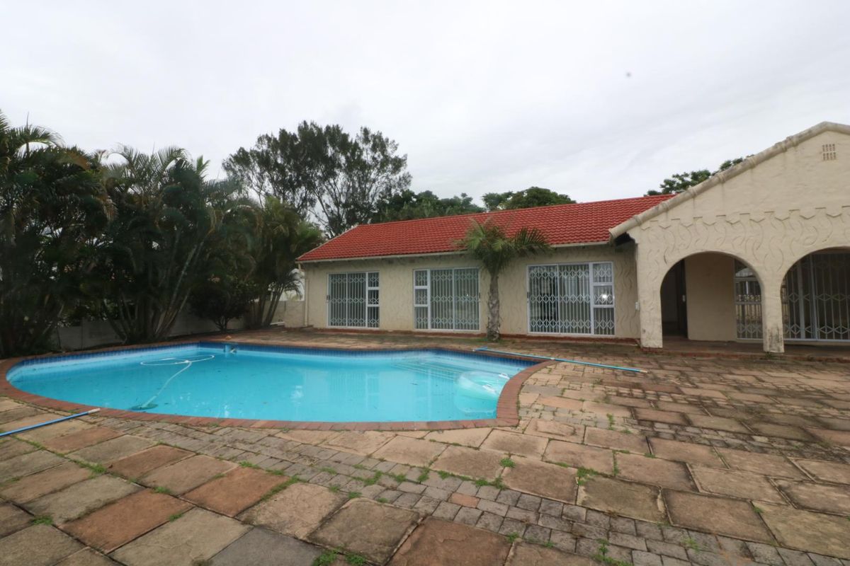 Rear exterior view featuring a swimming pool, paved patio area, and access to the main house through security-gated sliding doors.