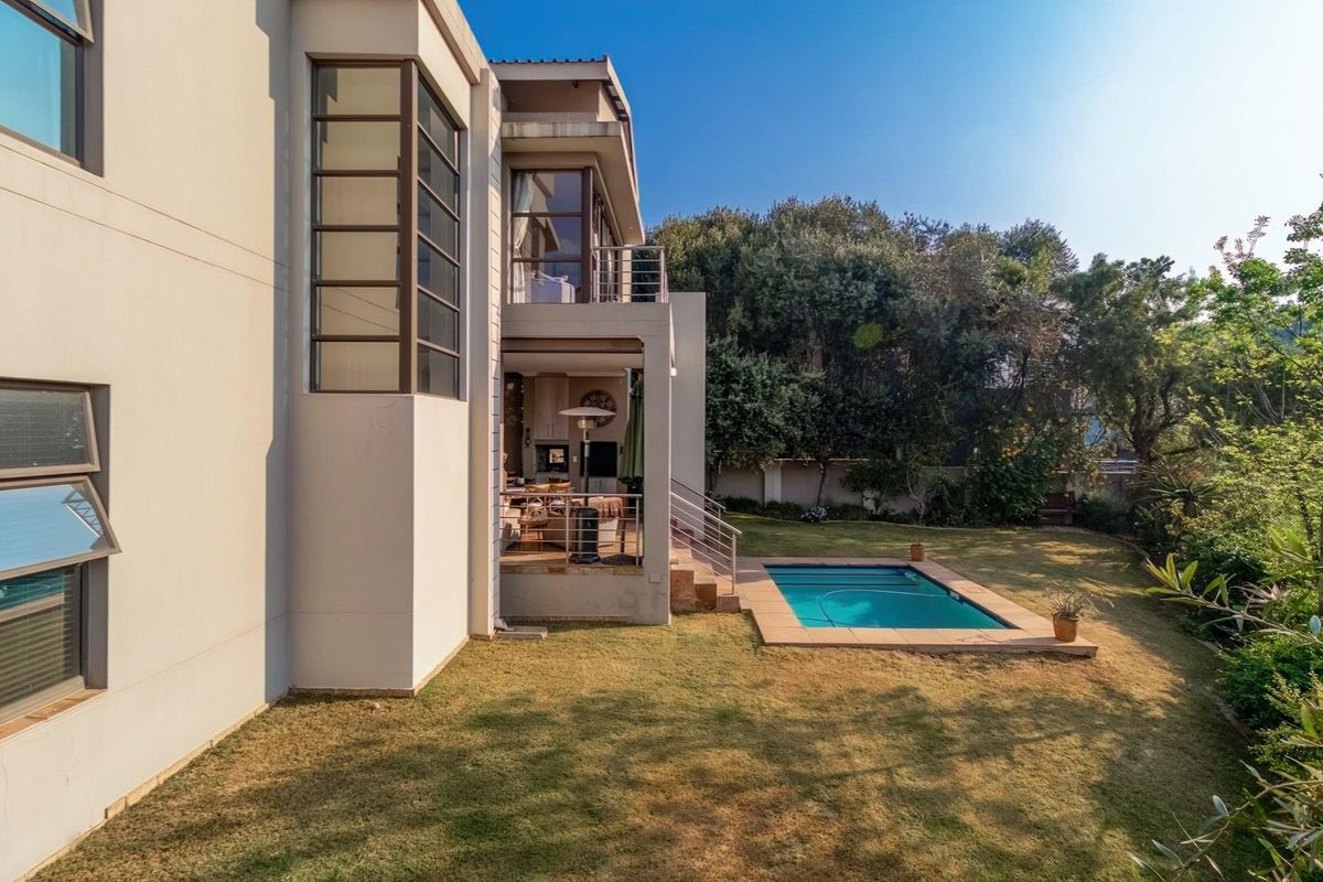 Rear view of the property featuring a covered patio, a swimming pool, and a landscaped garden area.