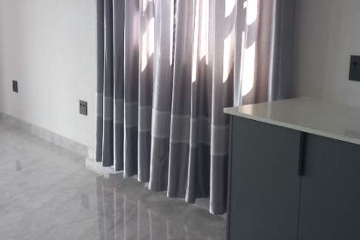 A modern interior space featuring polished grey floor tiles, a sleek dark grey built-in cabinet, and floor-to-ceiling curtains.