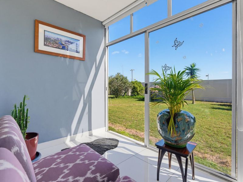 A bright, enclosed patio area featuring large sliding glass doors that provide direct access and views to the garden.