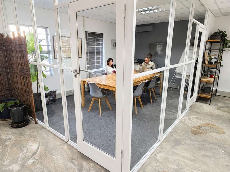 Modern office space featuring a glass-enclosed meeting room, polished concrete floors, and carpeted work areas with integrated air conditioning.