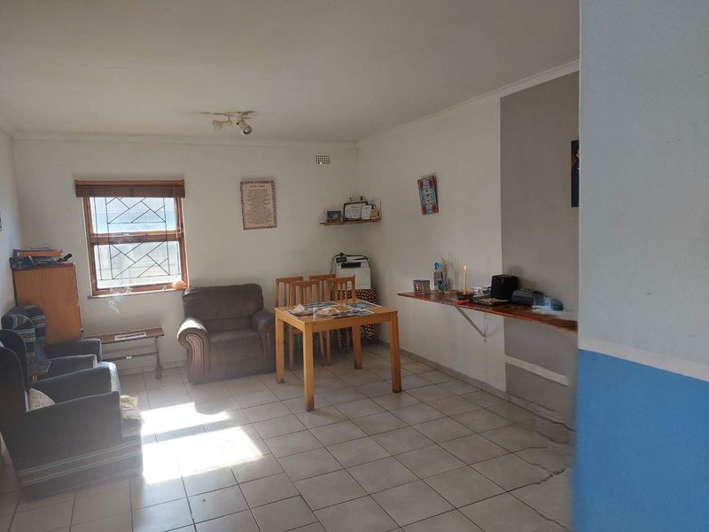 A living area featuring tiled flooring and a window with security bars, requiring cosmetic updates to improve the overall aesthetic and condition.