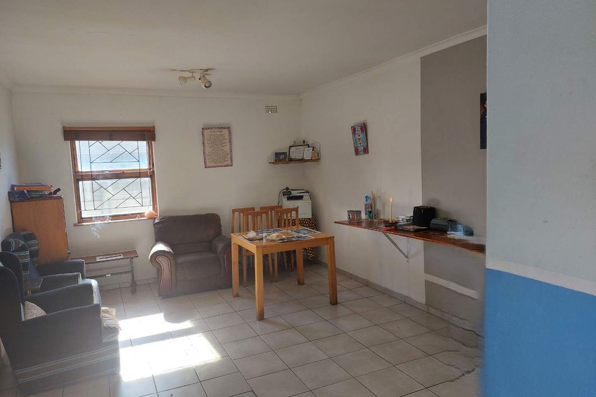 A living area featuring tiled flooring and a window with security bars, requiring cosmetic updates to improve the overall aesthetic and condition.