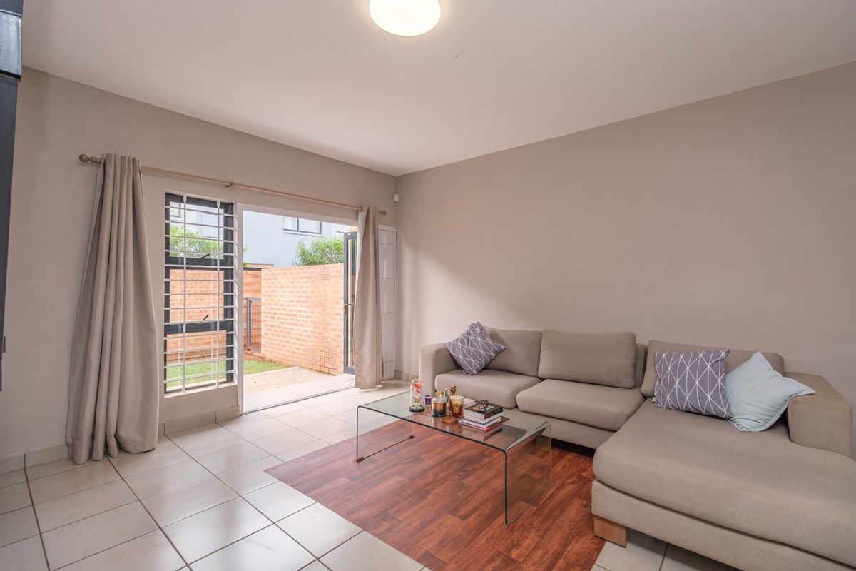 A bright living room featuring tiled flooring and a sliding glass door that provides direct access to the outdoor patio area.