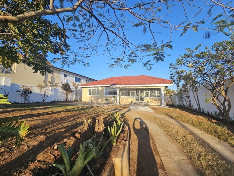 Front view of a single-story house featuring a tiled roof, concrete driveway, and established garden area with perimeter walling.