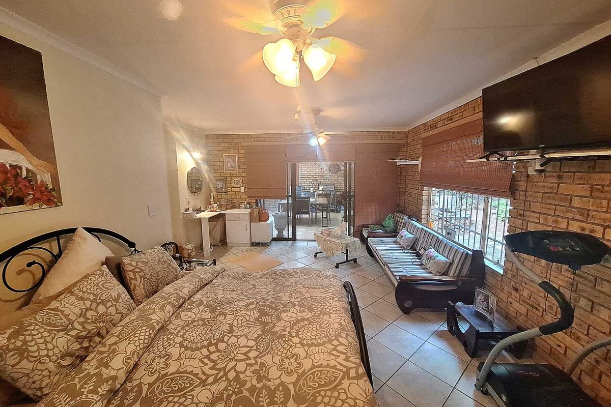 Spacious bedroom featuring exposed brick walls, tiled flooring, ceiling fans, and direct access to an outdoor patio area.
