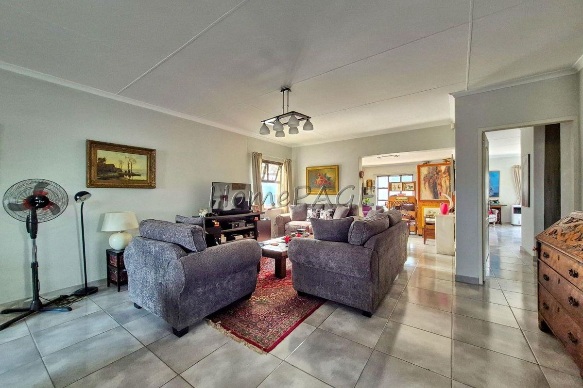 Spacious living room featuring neutral wall tones and tiled flooring, offering a comfortable and functional layout with easy access to adjacent living areas.