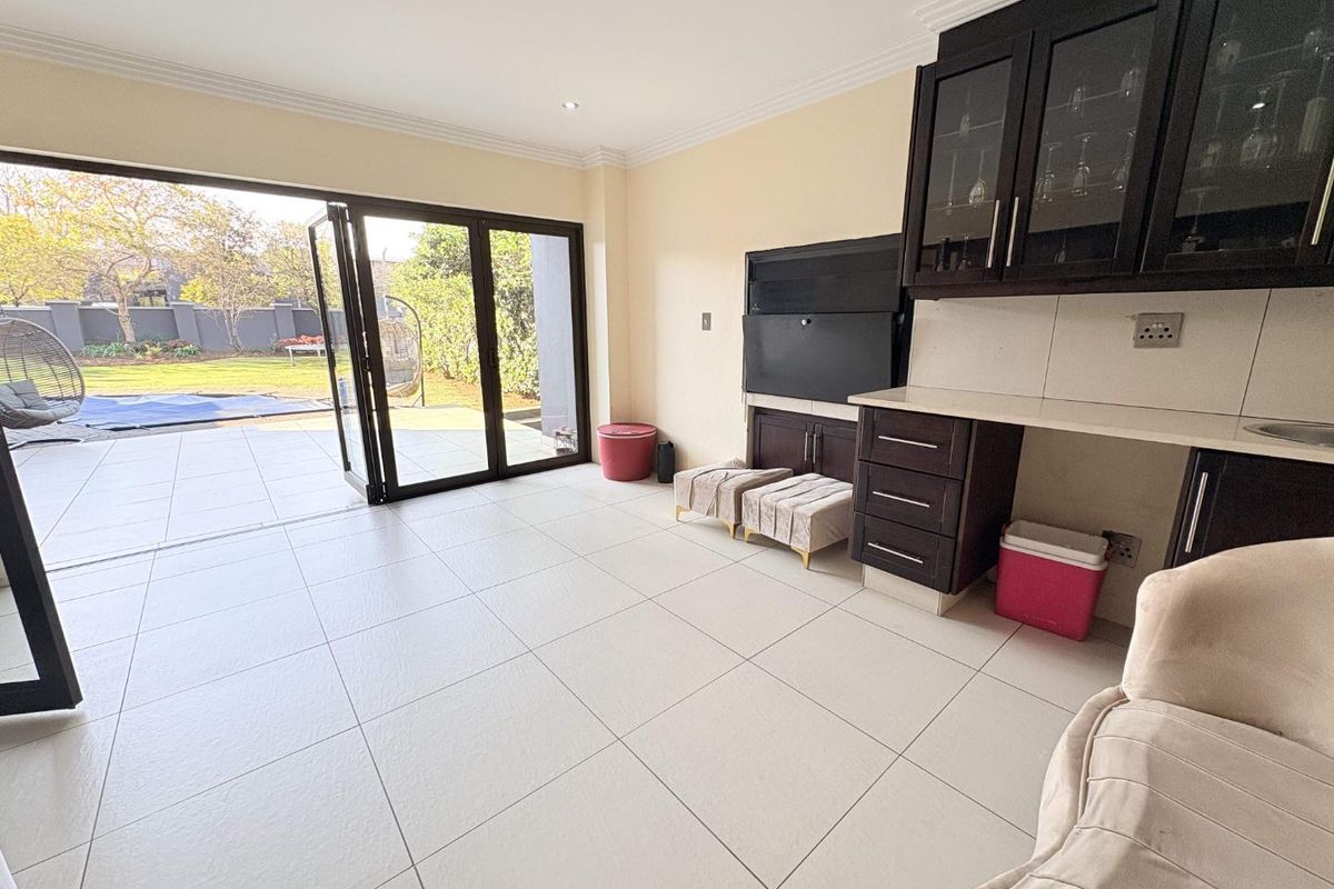 Spacious living area featuring tiled floors, built-in cabinetry, and large stacking glass doors providing seamless access to the outdoor patio and garden.