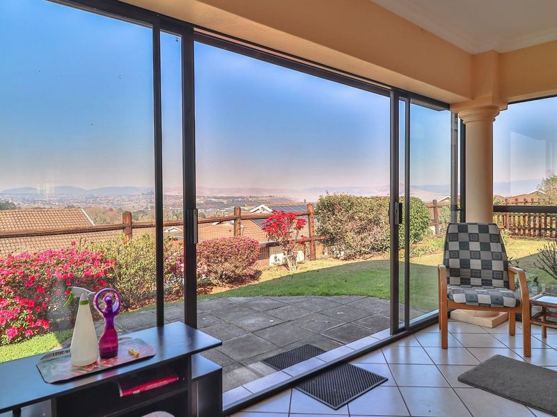 A covered patio area featuring large sliding glass doors that open onto a paved outdoor space with scenic views.