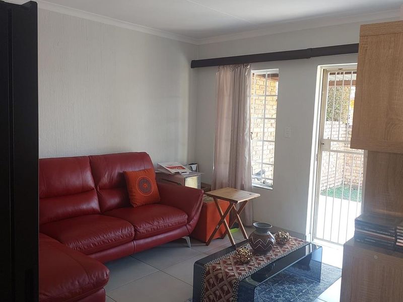 A living room featuring tiled flooring, a security gate leading to the exterior, and a ceiling-mounted spotlight.