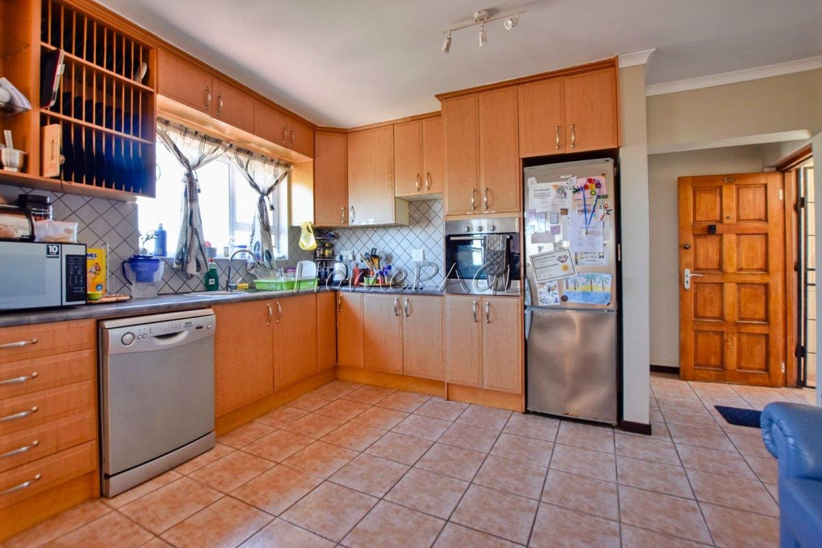 A functional kitchen featuring light wood cabinetry, tiled splashbacks, integrated oven, and tiled flooring, offering a practical layout for daily meal preparation.