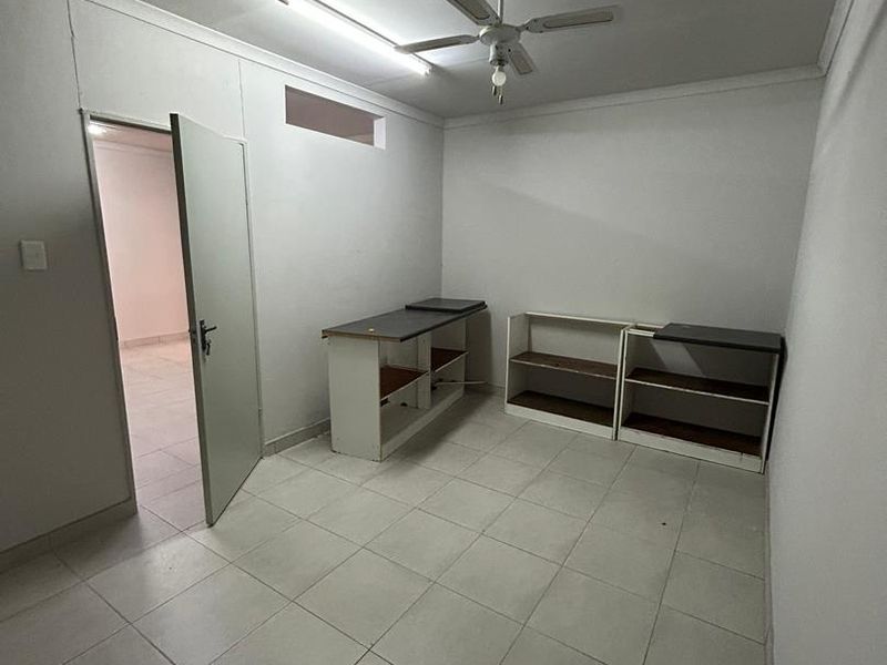 A functional utility space featuring tiled flooring, built-in shelving, and a ceiling fan, offering a versatile area for storage or workspace needs.