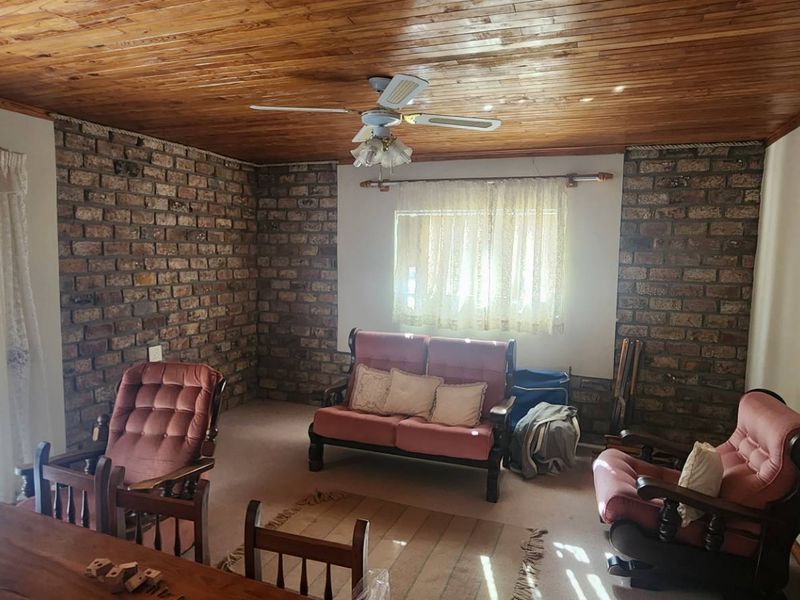 A living room featuring exposed brick walls and a timber tongue and groove ceiling, providing a rustic aesthetic with natural light.