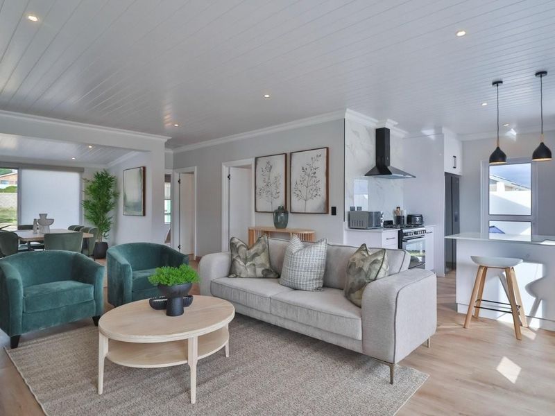 Modern open-plan living area featuring a contemporary kitchen with island, sleek cabinetry, and high-quality finishes, seamlessly flowing into a bright, comfortable lounge space.