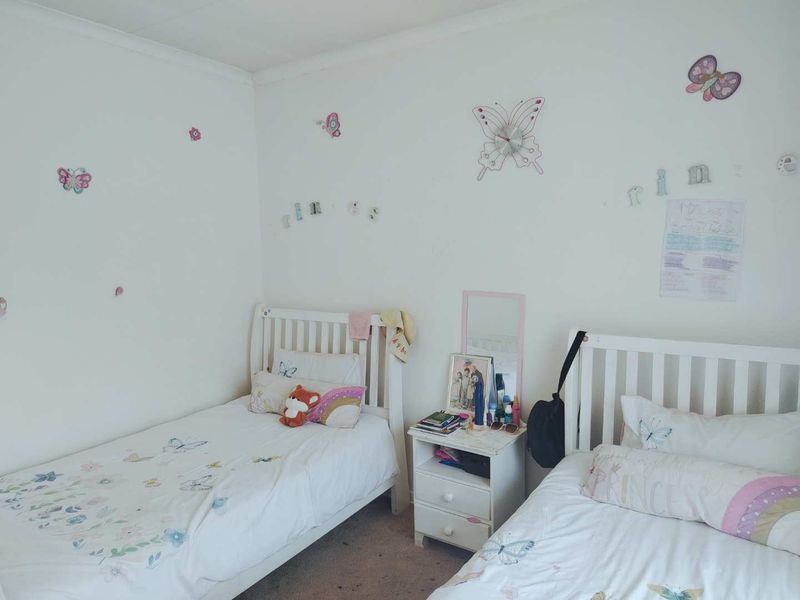 A bedroom featuring neutral walls and carpeted flooring, currently set up with twin beds.