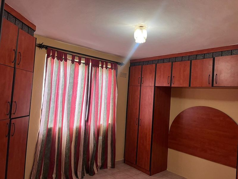 A bedroom featuring extensive built-in wooden cabinetry and tiled flooring, offering ample storage space.